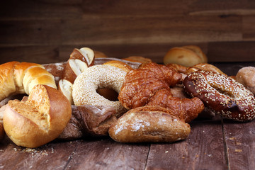 Different kinds of bread and bread rolls on board from above. Kitchen or bakery poster design.