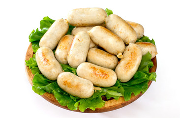 Homemade meat homemade grilled sausages and salad leaves on a wooden board on a white background.
