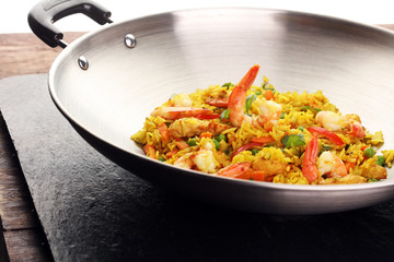 Udon stir-fry rice with shrimp and vegetables in wok pan on black burned stone background
