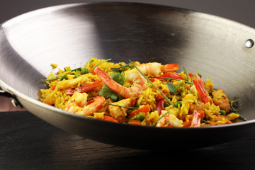 Udon stir-fry rice with shrimp and vegetables in wok pan on black burned stone background