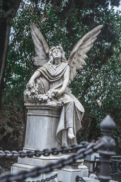 Sculpture of a sad angel on a cemetery against the background of leaves