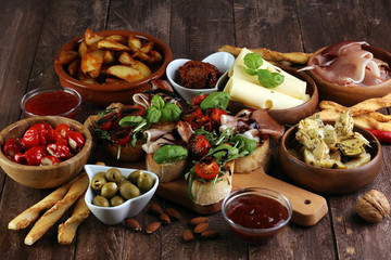 Italian antipasti wine snacks set. Cheese variety, Mediterranean olives, pickles, Prosciutto di Parma, tomatoes, artichokes and wine in glasses