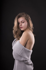 Naklejka premium Fashionable young woman posing in sweater with naked shoulders