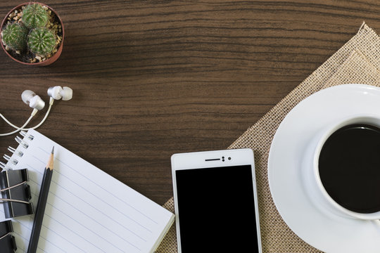 Cup of coffee and smartphone on wooden background