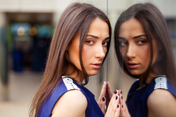 Stylish lady in blue dress posing near mirrored wall