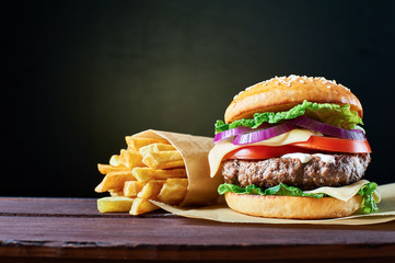 Craft beef burger and french fries on wooden table isolated on black background. - obrazy, fototapety, plakaty