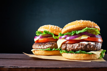 Two craft beef burgers on wooden table isolated on black  background. - obrazy, fototapety, plakaty