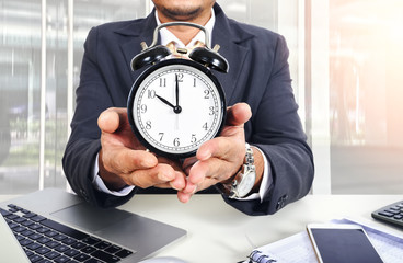 Close up of man holding alarm clock in the hands in office