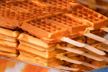 Freshly baked waffles on a stick, tasty dessert.