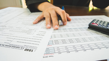 Business woman hand hold on the tax forms paper in business concept.