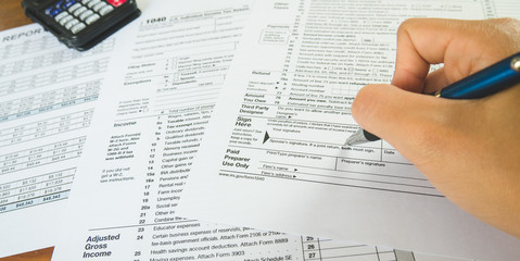 Hand hold pen on sign point on the tax forms paper in business concept