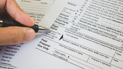 Fototapeta premium Hand hold pen on sign point on the tax forms paper in business concept