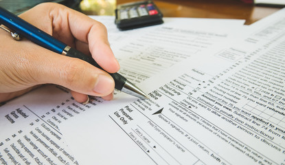 Obraz premium Hand hold pen on sign point on the tax forms paper in business concept