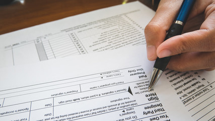 Hand hold pen on sign point on the tax forms paper in business concept