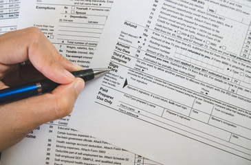 Hand hold pen on sign point on the tax forms paper in business concept