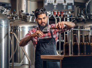 Indianr male manufacturer tasting and presenting craft beer in the microbrewery.