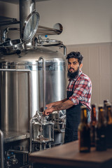 Indianr male manufacturer presenting craft beer in the microbrewery.