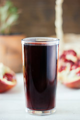 Pomegranate juice in glass surrounded by pomegranate halves.