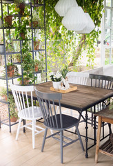 Dining room interior with table, chairs and plants against big windows