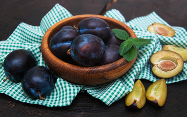 Bowl with  plums with green leaves