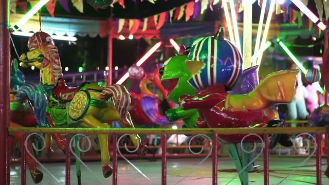 Scary animal carousel in colorful painting. Cheap Asian carnival fair ride