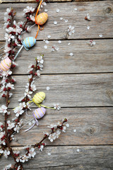 Tree branches with flowers and easter eggs on grey wooden table