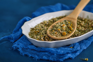 Dried chamomile or camomile flowers to make medicinal infusions  on a blue background