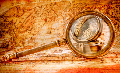 Vintage magnifying glass lies on an ancient world map