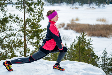 Naklejka premium Fit woman doing stretching exercises before running outdoors. Winter street training