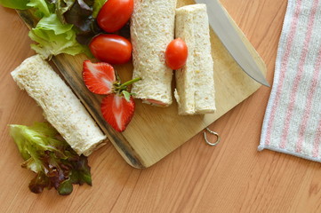 bread roll and salad on wooden cutting board