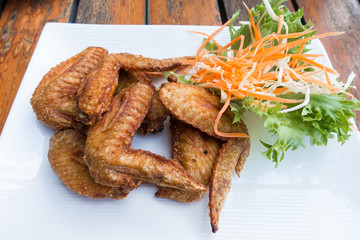 Chichen wing fried with salad in white dish on wooden table with copyspace ,flat lay