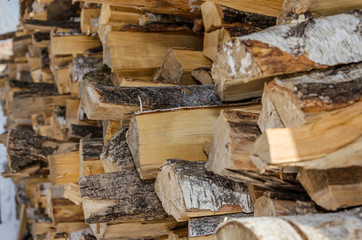 Neatly stacked logs of wood along a wooden wall
