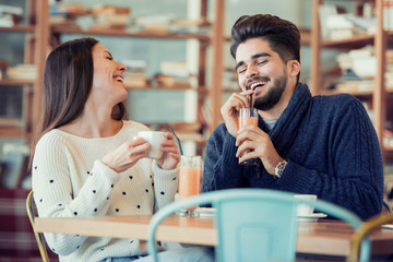 Young couple sitting in cafe and laughing