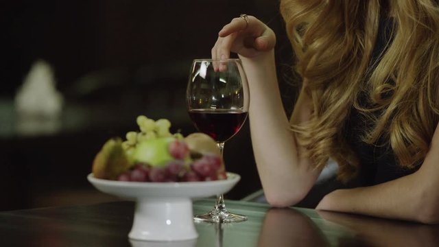 woman touching a glass of red wine in cafe