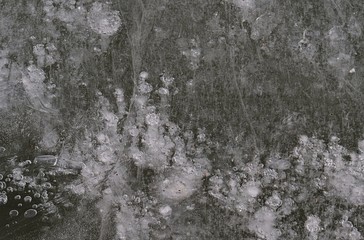Texture of thick layer of ice with bubbles and cracks on artificial fish pond reservoir