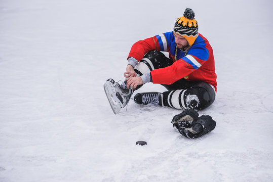 hockey player sitting on the ice to tie shoelaces