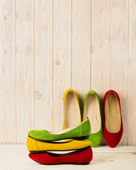 Red, green and yellow women's shoes (ballerinas) on wooden background.