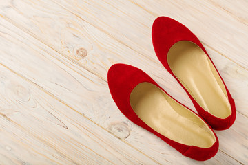 Red women's shoes (ballerinas) on wooden background.
