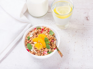 Fototapeta na wymiar Healthy breakfast - white plate of granola with orange slices, mint and seeds