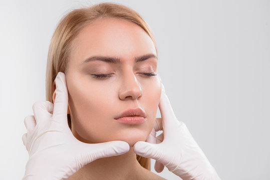 Surgeon examining face of young woman