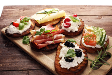 Bread Brushetta or authentic traditional spanish tapas set for lunch table. Sharing antipasti on party or summer picnic time over wooden rustic background.