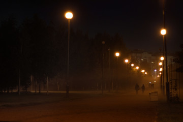 Misty alley, lighted lamps, receding into the distance couple holding hands