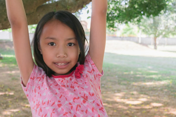 Close up happy adorable asian children wear red dress joyful with climbing trees .