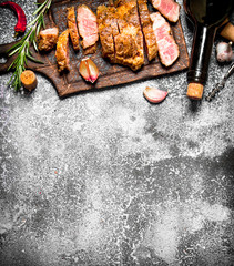 Meat grill. Sliced grilled pork with red wine. On rustic background.