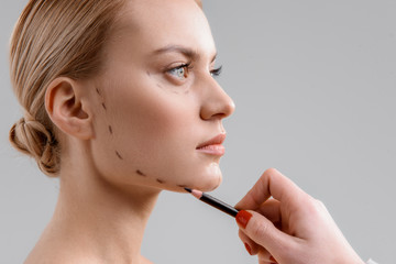 Professional doctor preparing patient for facial surgery