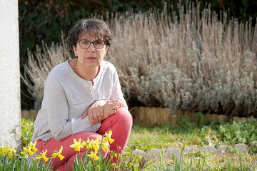 brunette mature woman in her garden with daffodils