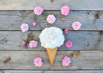 White rose flower and pink roses flowers in ice cream cone on rustic wooden background - flowers composition. Stylish flat lay. Minimal and spring concept.