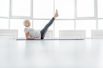 Fototapeta na wymiar Healthy old lady exercising on mat