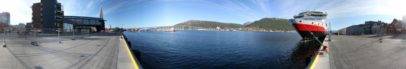 Panorama vom Hafen von Tromso, Norwegen, mit Kreuzfahrtschiff, Hotels, Brücke und Eismeerkathedrale im Hintergrund