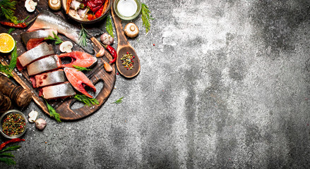 Obraz na płótnie Canvas Raw fish. A piece of fresh salmon with spices on old cutting Board. On the rustic table.